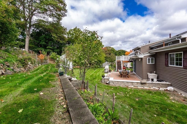 view of yard with a patio area, fence, and stairs