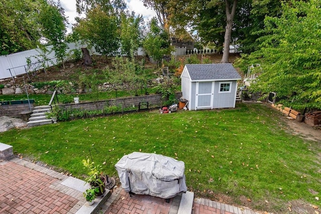view of yard featuring a storage shed, a fenced backyard, a patio area, and an outbuilding