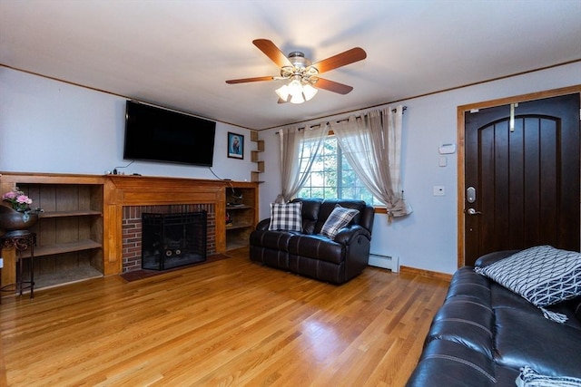 living room with baseboards, ceiling fan, a fireplace, baseboard heating, and wood finished floors