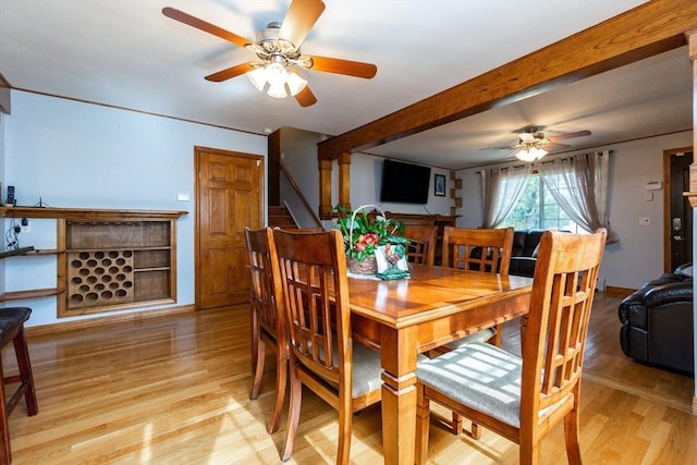 dining room with light wood-type flooring, a ceiling fan, stairs, baseboards, and beam ceiling