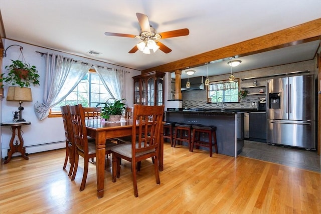 dining space with baseboard heating, light wood finished floors, visible vents, and a ceiling fan