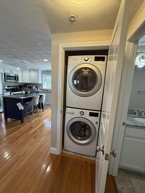 146 Main St Unit 2D, Clinton, MA 01510 - clothes washing area featuring estacked washer and dryer, light wood-style floors, and a sink