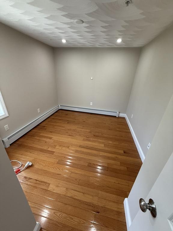 146 Main St Unit 2D, Clinton, MA 01510 - empty room with a baseboard heating unit, light wood-style floors, and baseboards