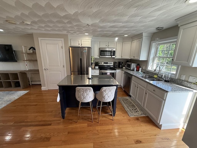 146 Main St Unit 2D, Clinton, MA 01510 - kitchen with appliances with stainless steel finishes, a sink, a kitchen breakfast bar, a kitchen island, and light wood-type flooring