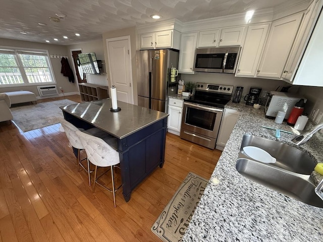 146 Main St Unit 2D, Clinton, MA 01510 - kitchen featuring stainless steel appliances, white cabinetry, open floor plan, light wood finished floors, and a wall mounted AC