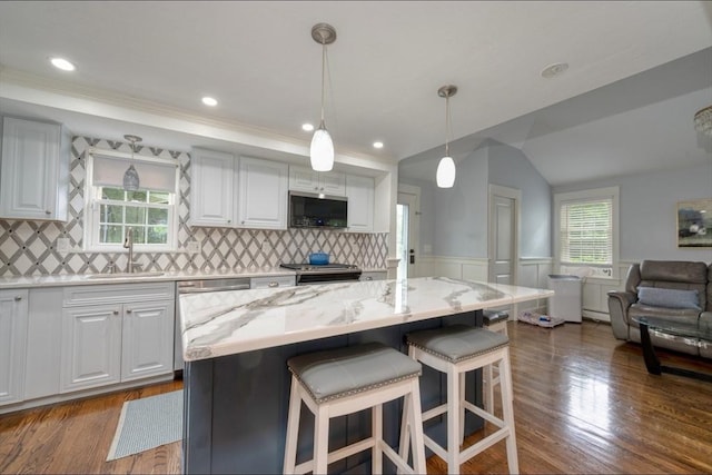 67 Raymond Rd, Plymouth, MA 02360 - kitchen featuring stainless steel appliances, light stone countertops, white cabinetry, a wainscoted wall, and a breakfast bar area