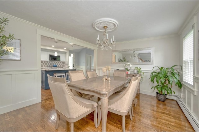 67 Raymond Rd, Plymouth, MA 02360 - dining area with a chandelier, baseboard heating, a decorative wall, light wood finished floors, and ornamental molding