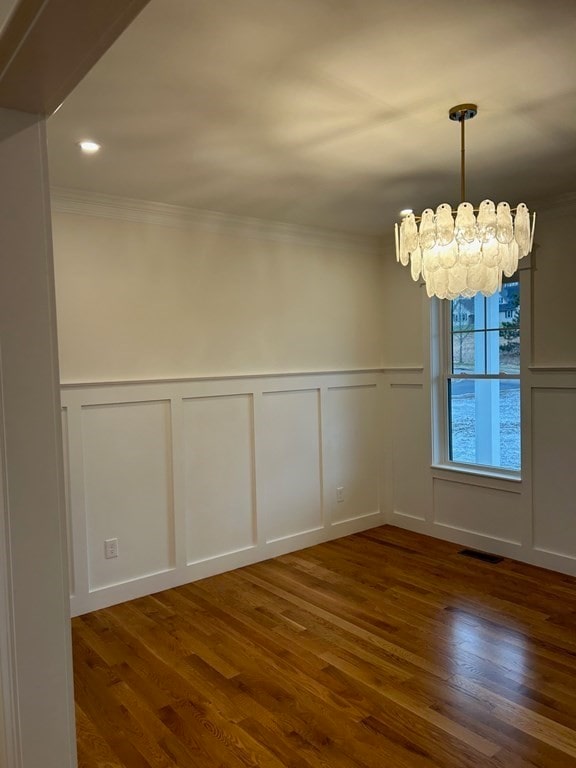 unfurnished room with ornamental molding, a notable chandelier, and dark hardwood / wood-style floors