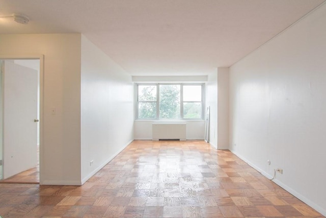 spare room with radiator heating unit and baseboards