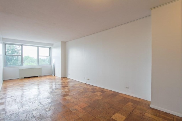 spare room with baseboards and radiator