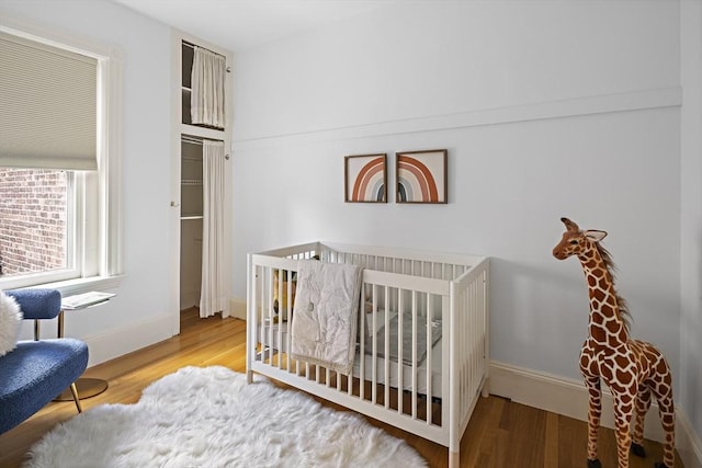 bedroom with wood finished floors, baseboards, and a crib