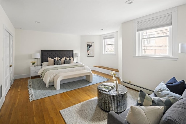 bedroom featuring recessed lighting, a baseboard radiator, baseboards, and wood finished floors