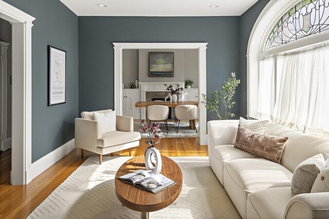 living area with light wood finished floors, a fireplace, and baseboards