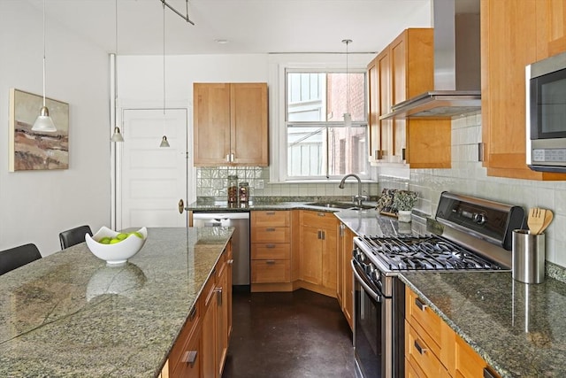 kitchen with appliances with stainless steel finishes, decorative light fixtures, wall chimney exhaust hood, decorative backsplash, and a sink