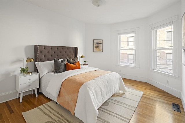 bedroom with light wood-style flooring, baseboards, and visible vents
