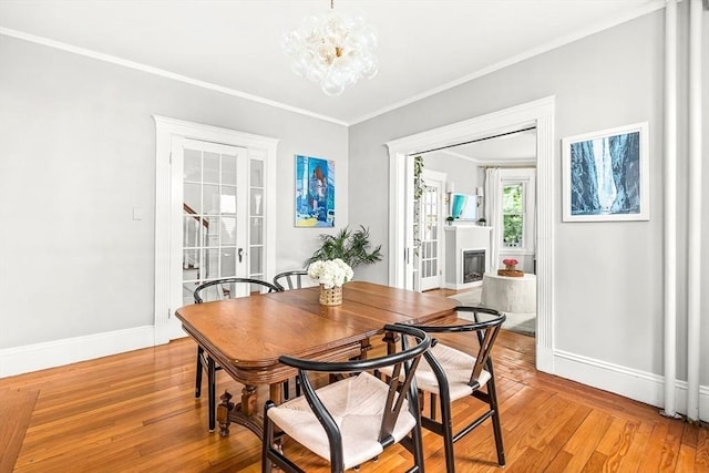 115 Westbourne Ter Unit 1, Brookline, MA 02446 - dining area with light wood finished floors, a chandelier, ornamental molding, and a fireplace