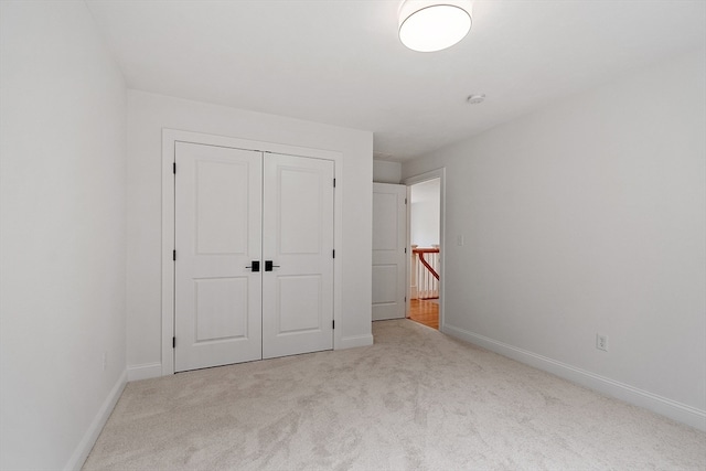 unfurnished bedroom featuring light colored carpet and a closet