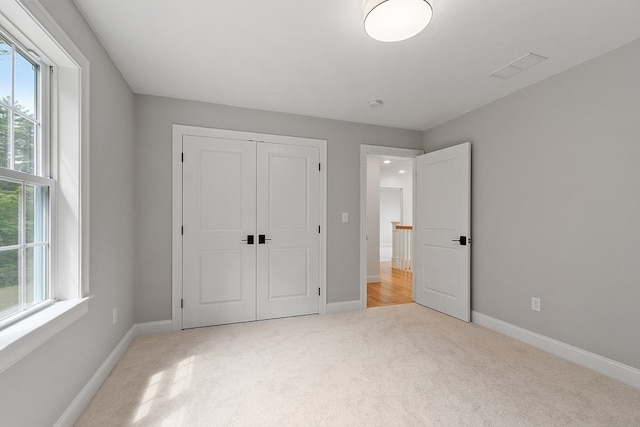 unfurnished bedroom with a closet, multiple windows, and light colored carpet