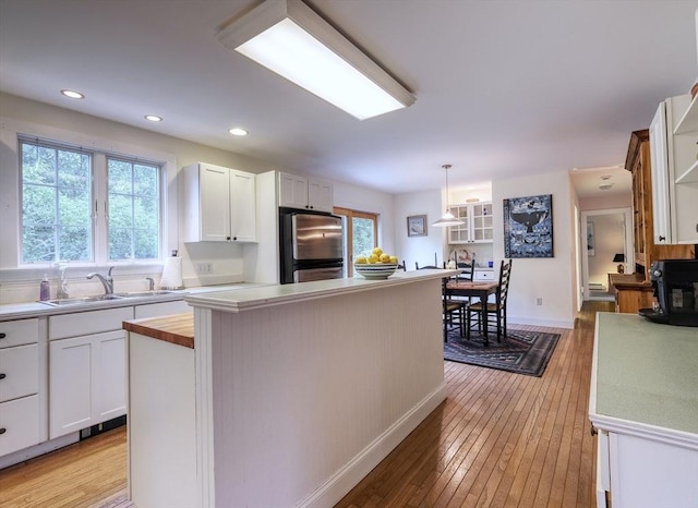 250 S Eastham St, Eastham, MA 02642 - kitchen featuring freestanding refrigerator, a sink, light wood-style flooring, white cabinetry, and decorative light fixtures