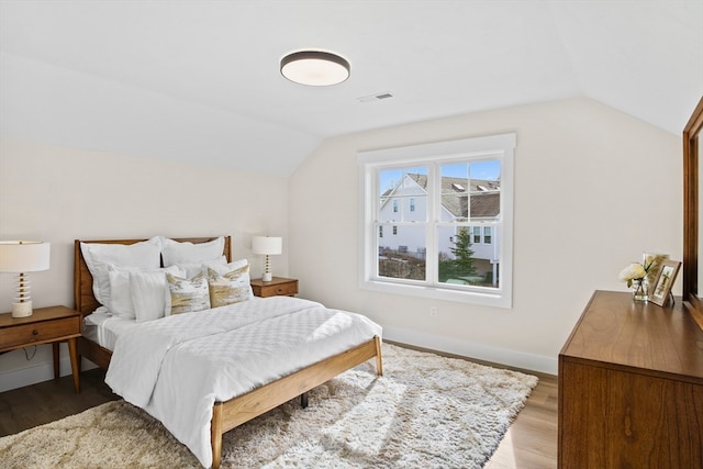 bedroom featuring light wood-type flooring and vaulted ceiling