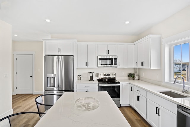 kitchen featuring white cabinets, light stone countertops, stainless steel appliances, dark hardwood / wood-style flooring, and sink