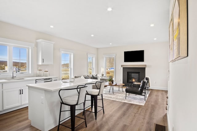 kitchen featuring hardwood / wood-style floors, a kitchen island, white cabinetry, and sink