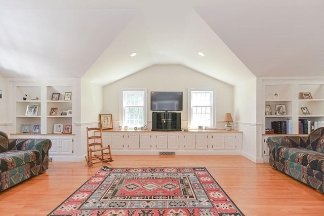 living room with light hardwood / wood-style floors, vaulted ceiling, and built in features