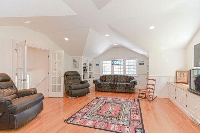 living room with french doors, lofted ceiling, built in shelves, and light hardwood / wood-style floors