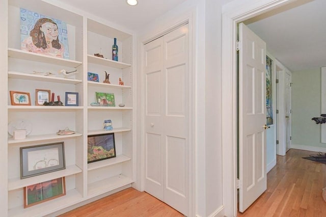 hallway with light hardwood / wood-style floors and built in shelves