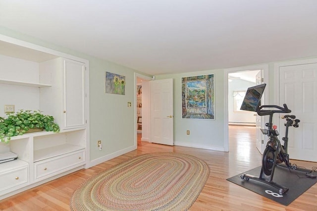 workout area with a baseboard radiator and light wood-type flooring