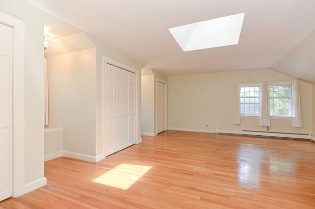 bonus room featuring light wood-type flooring, lofted ceiling with skylight, and baseboard heating