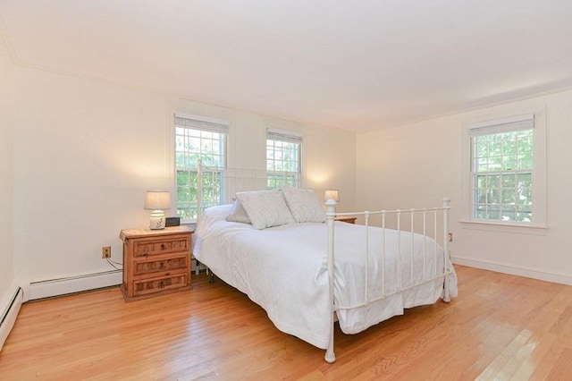 bedroom featuring a baseboard heating unit and hardwood / wood-style floors