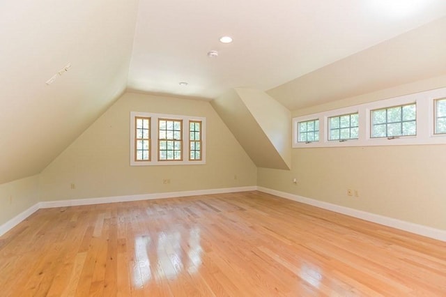 additional living space with light hardwood / wood-style flooring and vaulted ceiling