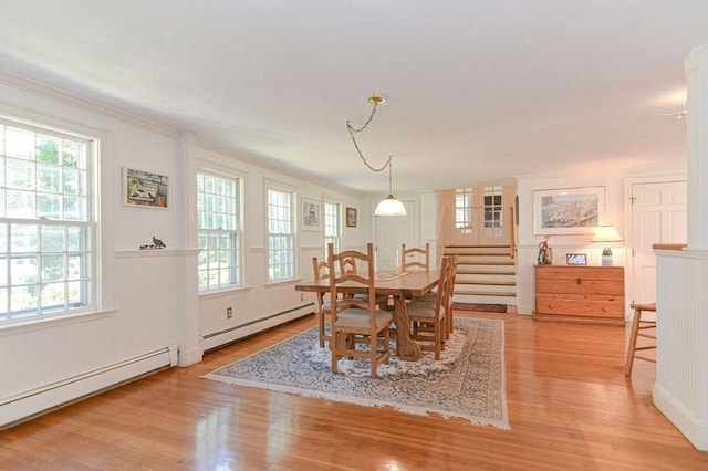 dining space with crown molding, a baseboard radiator, and light wood-type flooring