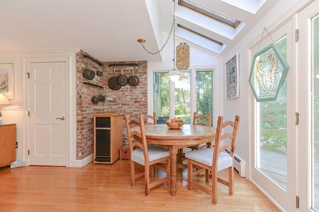 dining area with baseboard heating, vaulted ceiling with skylight, and light hardwood / wood-style flooring