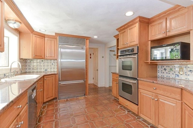 kitchen featuring tasteful backsplash, sink, light stone countertops, and appliances with stainless steel finishes