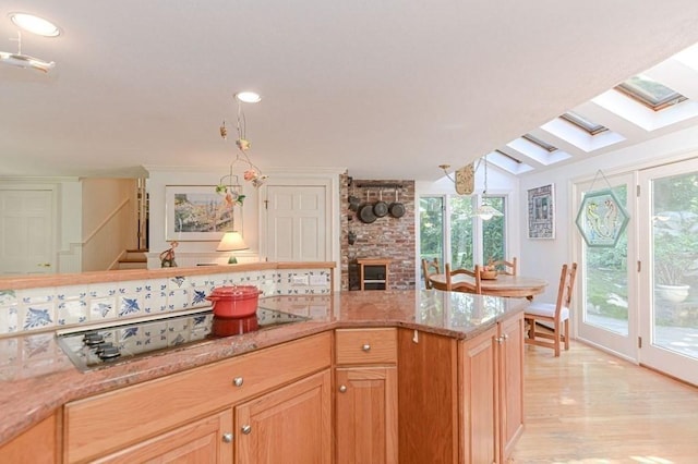 kitchen with light stone counters, plenty of natural light, stovetop, and light wood-type flooring