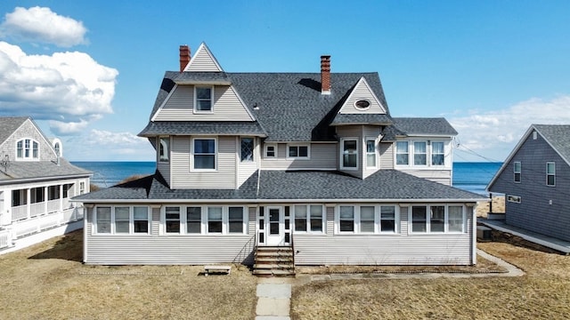 back of property featuring a water view and a yard