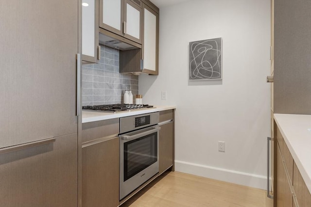 kitchen with backsplash, light hardwood / wood-style flooring, and stainless steel appliances