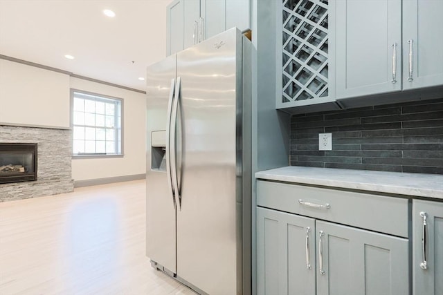 515 Centre St Unit 2, Newton, MA 02458 - kitchen with stainless steel fridge with ice dispenser, tasteful backsplash, light countertops, gray cabinets, and a glass covered fireplace