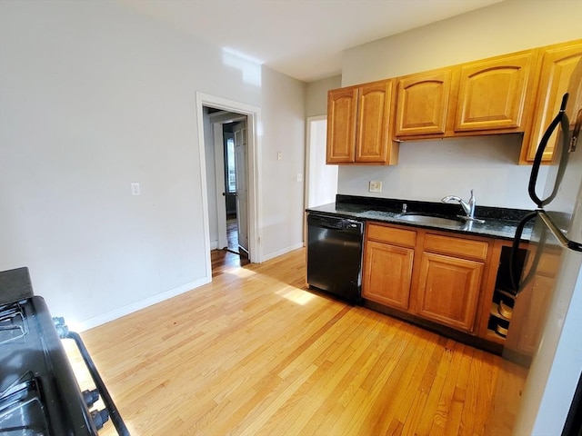 kitchen with refrigerator, black dishwasher, dark stone countertops, sink, and light hardwood / wood-style flooring