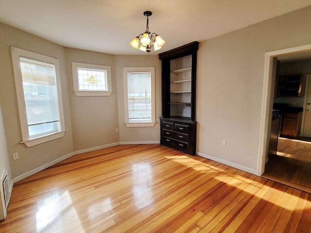 empty room featuring light hardwood / wood-style floors and a chandelier