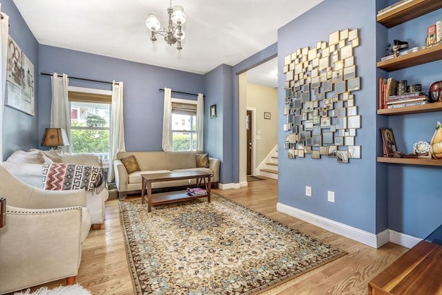 sitting room with stairs, a chandelier, wood finished floors, and baseboards