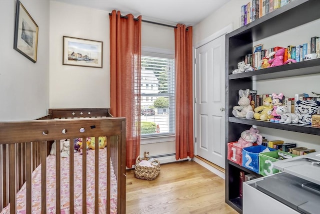 bedroom featuring multiple windows, light wood finished floors, and a crib