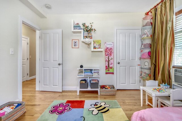 recreation room featuring wood finished floors, baseboards, and cooling unit