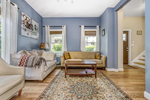 living room featuring wood finished floors, stairs, and baseboards