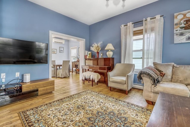 living room with a wall mounted AC, baseboard heating, and wood finished floors