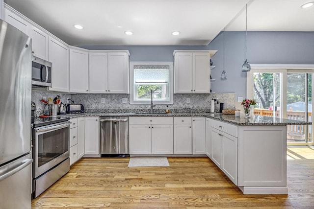 kitchen featuring appliances with stainless steel finishes, a sink, a peninsula, plenty of natural light, and recessed lighting