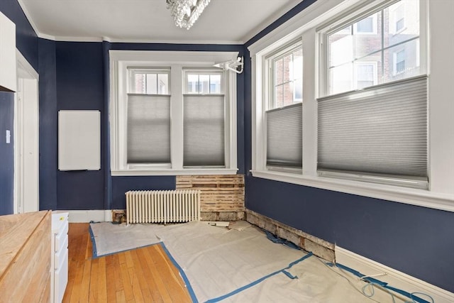 interior space with radiator, wood-type flooring, and ornamental molding