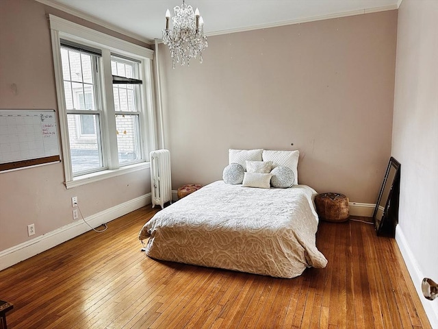 bedroom with radiator, ornamental molding, hardwood / wood-style floors, and a chandelier